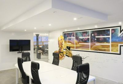 Modern meeting room with a white table and large space-themed mural.