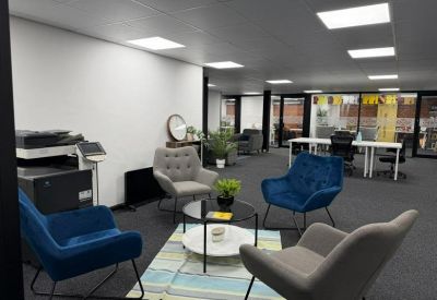 Communal lounge area with blue and grey armchairs, a coffee table, and a striped rug.