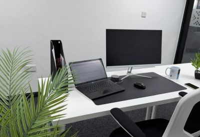 Minimalist white workstation with a laptop, monitor, and a white ergonomic chair.