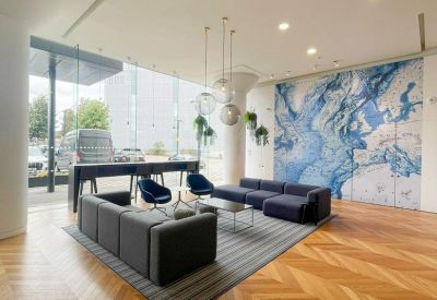 Lounge area with grey and navy sofas on a striped rug and a blue abstract feature wall.