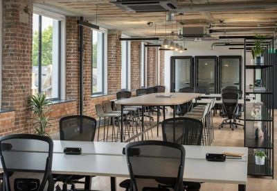 Open-plan coworking space with brick pillars and communal wooden tables.