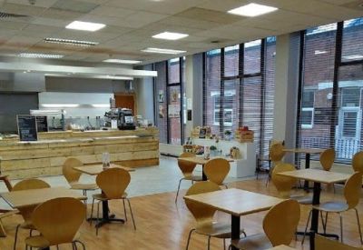 Spacious cafe breakout area with wooden floors and large windows.