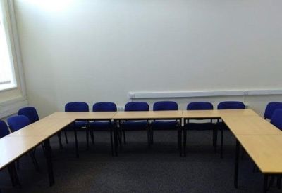 U-shaped meeting room setup with blue chairs and light wood tables.