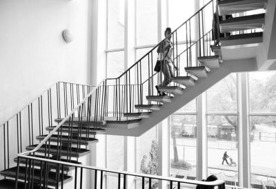 Black and white view of a modern open-tread staircase with person walking.