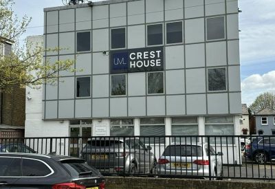 Exterior view of the grey-facade building at Crest House with parking in front.