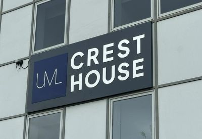 Close-up of the Crest House building signage on the grey exterior wall.