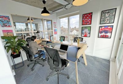 Modern coworking space with vibrant artwork and a person working at a desk.