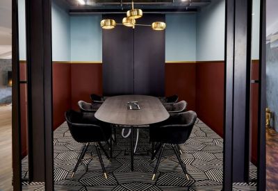 Sophisticated meeting room with a dark oval table, velvet chairs, and a gold light fixture.