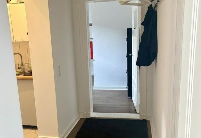 Entrance hallway featuring a coat rack and a glimpse into the kitchen area.