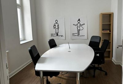 Private four-person office suite with a white oval table and playful wall art.