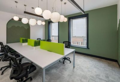 Shared desk space with lime green dividers and multiple white globe lights overhead.