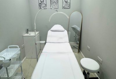 Clinical treatment room with a white adjustable medical bed and ring light.