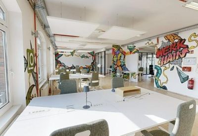 Spacious open coworking area with wooden floors and colorful graffiti wall art.