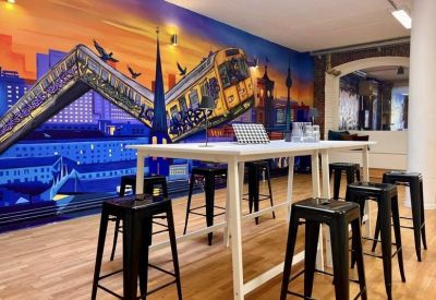 High table with stools set against a mural of a train at sunset.