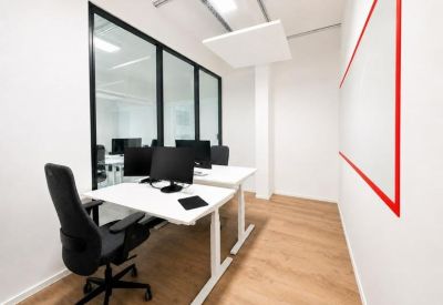Bright white office suite with two desks and glass partition walls.