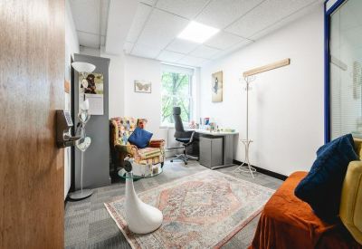A cozy lounge or breakout area featuring a colourful patchwork armchair and a decorative rug.