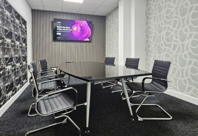 Co-working space with a mix of desk seating and a padded bench area near the window.