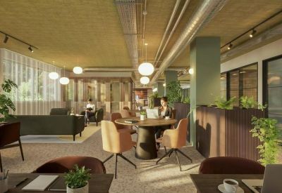 Communal lounge with industrial ceilings, green pillars, and velvet armchairs.