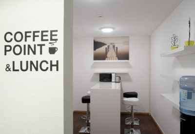Communal break area with high white tables, bar stools, and coffee point signage on the wall.
