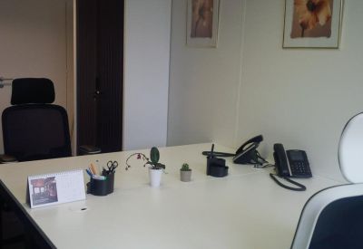 Private office space with a large white desk, ergonomic chairs, and framed artwork on the wall.