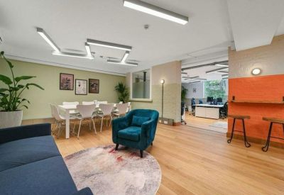 Bright lounge area with a teal velvet armchair and orange accent wall.