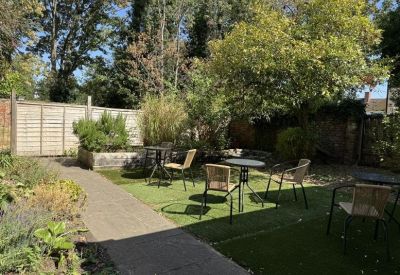 Enclosed outdoor courtyard with seating areas, wooden fencing, and mature trees.