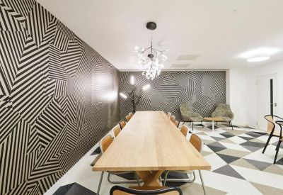 Modern meeting room with a long wooden table and bold geometric patterned wallpaper.