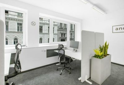 Bright office workspace with adjustable desks, ergonomic chairs, and large windows.
