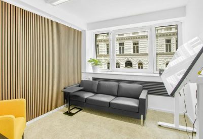 Relaxing lounge area with a dark leather sofa and a decorative slatted wood wall.