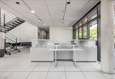 Bright modern reception lobby featuring a white desk and industrial-style staircase.