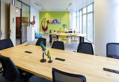 Open-plan office space featuring a green accent wall and various workstations.