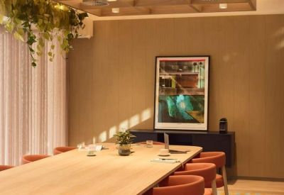 Professional meeting room with a large wooden table and comfortable orange seating.