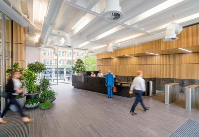 Spacious reception lobby with a dark marble desk, wood-paneled walls, and indoor plants.