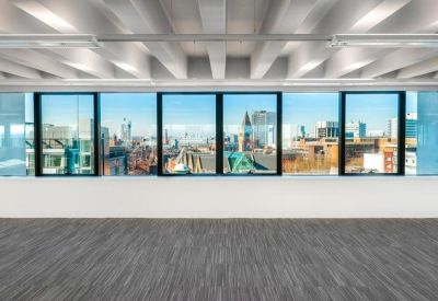 Large empty office floor with grey carpeting and panoramic windows showing the city skyline.