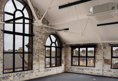 Bright workspace with high arched windows and white brick walls.