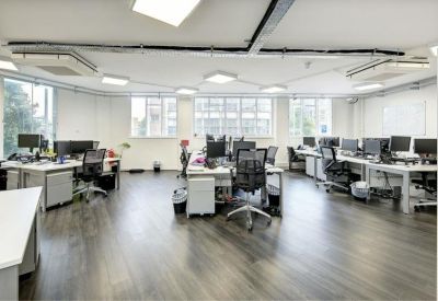Spacious workstation area featuring large windows, modern lighting, and multiple computer monitors.