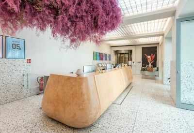 Reception area with a light wood curved desk and a large pink floral ceiling installation.