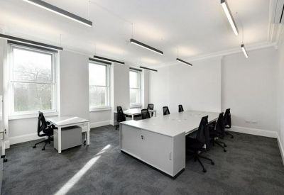 Bright open-plan office with white desks and black ergonomic chairs.