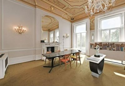 Grand meeting room with ornate ceiling details, a fireplace, and large windows.