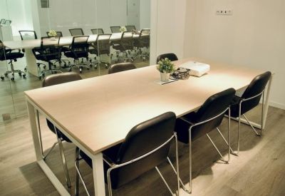 Small meeting room with a wooden table, black chairs, and natural light.