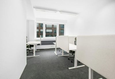 Bright workspace with height-adjustable white desks and privacy dividers.