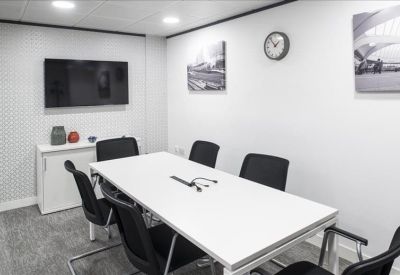 White conference room with a large screen and black mesh chairs.