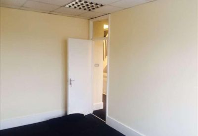 Private office with white walls, carpeted floor, and an open door leading to a hallway.