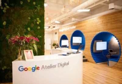 Google Atelier Digital reception area featuring a green plant wall and blue seating pods.