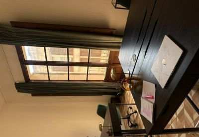 Close-up of a black desk with a laptop near a sunlit window.