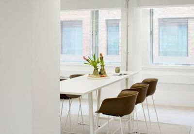Breakout area with high white table, brown bar stools, and fresh flowers.