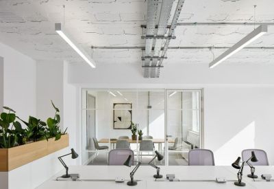 Bright workspace featuring white desks, task lamps, and indoor plants.