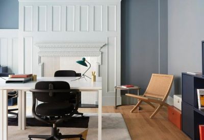 Meeting space with a white paneled feature wall and a mid-century modern lounge chair.