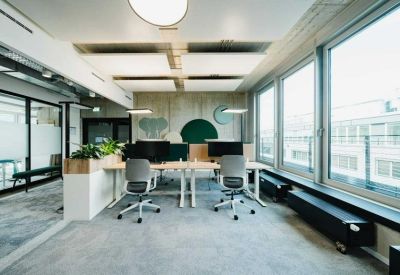 Bright workspace featuring several height-adjustable desks and green wall art.