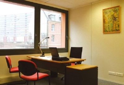 Private office featuring two red chairs, a wooden desk with a laptop, and large windows.
